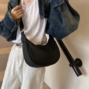 Détail du sac bandoulière en cuir noir en forme de croissant avec une texture grainée