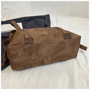 Détail du sac cabas marron montrant la base en cuir surpiqué et la boucle en métal