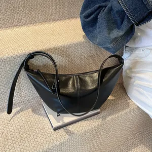 Detalle de bolso medialuna negro en ecopiel con costura vertical y correa de hebilla