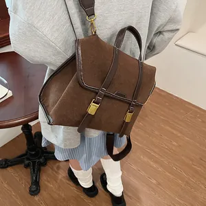 Close-up of retro brown matte suede backpack with contrast stitching and gold buckles