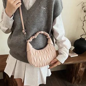 Detail of a pink ruched handbag featuring soft pleated texture and a unique ruffled handle