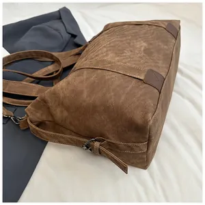 Détails d'un sac cabas en toile marron avec empiècement cuir et boucle en métal