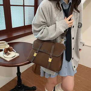 Detailed view of brown matte leather messenger bag with gold buckles in cozy setting