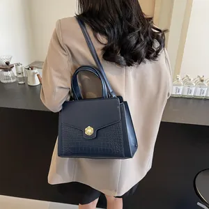 Detail of navy blue croc-embossed leather tote bag with elegant gold pearl clasp