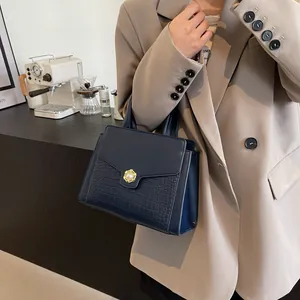 Structured navy blue handbag with embossed crocodile pattern and elegant pearl gold clasp