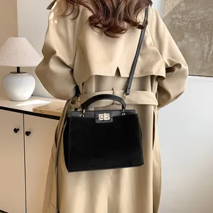 Vue détaillée du sac Kelly noir en mélange de cuir porté avec un trench-coat beige chic
