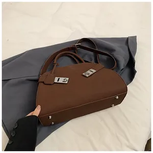 Side view of dark brown leather tote bag showing silver metal buckles and bottom studs