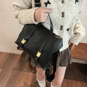 Detail of vintage black leather tote with white stitching and gold hardware on model