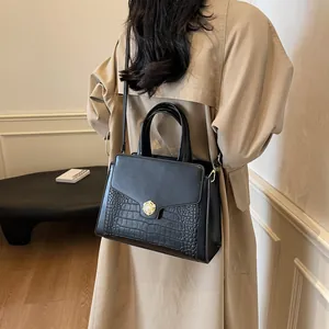 Detail of black faux crocodile leather tote bag with elegant pearl gold flower clasp