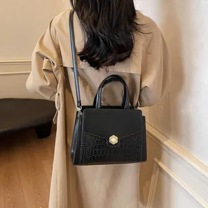 Lifestyle shot of black crocodile texture tote bag with pearl flower clasp on trench coat