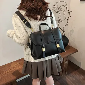 Rear view of model wearing a vintage black leather backpack with gold buckle details