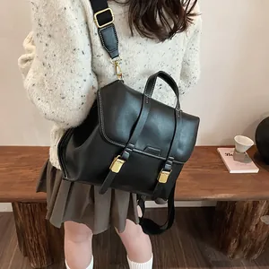 Detail of vintage black matte backpack with white stitching and gold buckles on a model