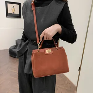 Sac à main Kelly marron en daim porté par un mannequin dans un studio minimaliste