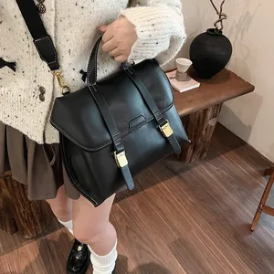 Detail of matte leather satchel featuring contrast stitching and gold metal buckles