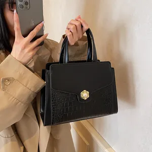 Detail of black faux leather tote with crocodile texture and pearl gold buckle clasp