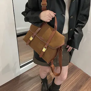 Detail of vintage brown suede satchel with leather trim and gold metal buckles