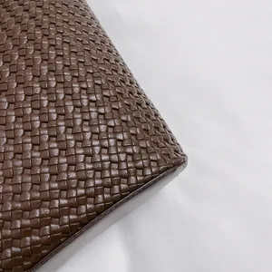 Detailed close-up of dark brown woven leather texture on a luxury shoulder tote bag