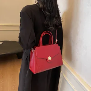 Detail of red crocodile texture handbag with gold pearl clasp and leather shoulder strap