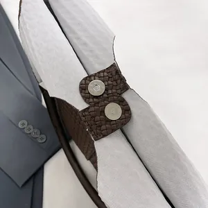Close-up of dual magnetic snaps and gray fabric lining inside a brown woven tote bag