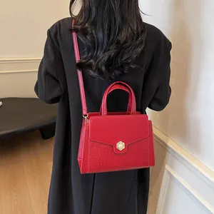 Detail of red crocodile texture tote with pearl lock carried over a black coat