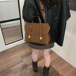 Detail view of a vintage brown leather bag with buckle straps and wide shoulder strap