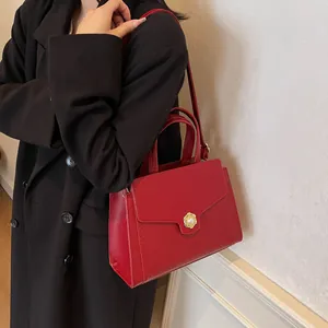 Close-up of red crocodile pattern tote with a golden petal pearl clasp and thin strap