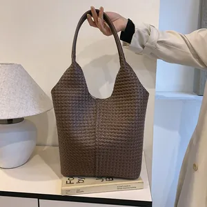 Close-up of woven texture on dark brown leather tote bag with smooth handle detail