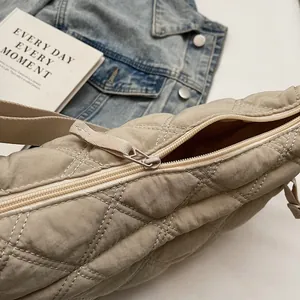 Detail of beige quilted dumpling bag with smooth zipper and durable woven strap