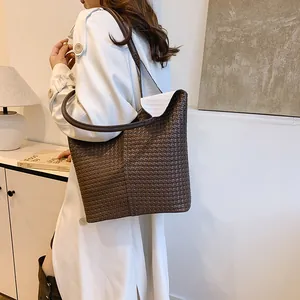 Detail of dark brown woven leather tote bag texture and long shoulder strap for commuting