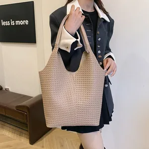 Detail shot of the woven leather texture and handles on this beige commute tote bag