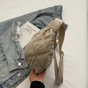 Close-up of beige quilted crossbody bag with diamond stitching and canvas strap