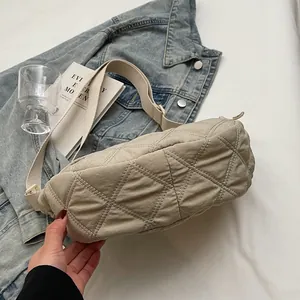 Detail of beige quilted puffer bag with contrast stitching and wide shoulder strap