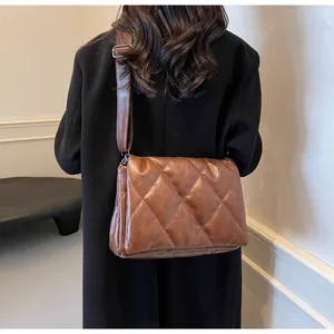 Détail d'un sac bandoulière matelassé marron avec surpiqûres losanges et bandoulière