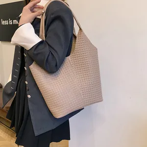 Close-up of beige woven texture tote bag showing refined leather craftsmanship and strap