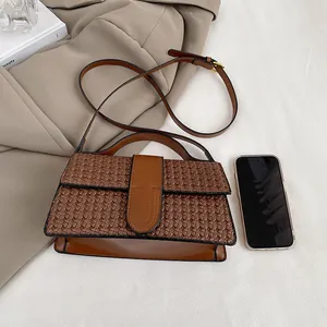 Detailed view of brown woven texture handbag with adjustable strap and top handle