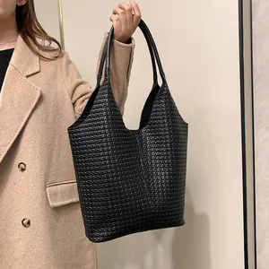 Detailed view of black woven leather tote bag with V-shaped opening and slim handles
