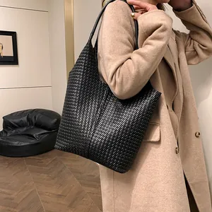 Detailed view of the black woven tote bag with premium leather texture on a female model