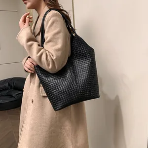 Detail shot of the black woven leather texture on a spacious commute tote bag