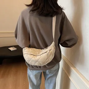 Detail view of beige quilted crescent bag with adjustable wide strap and zipper closure