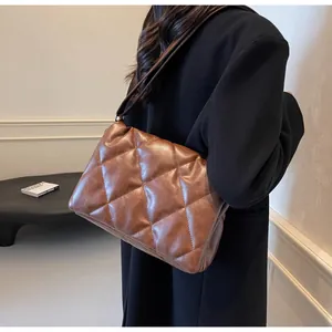 Détail du sac bandoulière matelassé marron foncé avec texture brillante et large sangle
