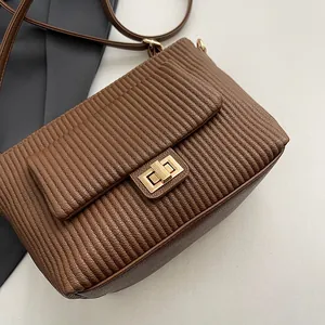 Dettaglio borsa in pelle sintetica marrone trapuntata con strisce verticali e chiusura oro