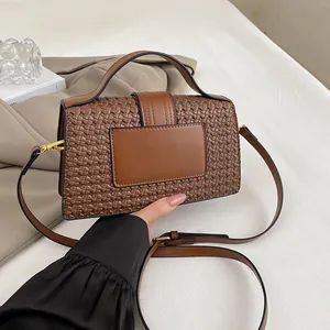 Macro detail of the woven leather texture and gold hardware on the brown handbag