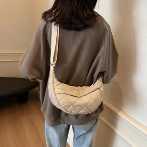 Rear view of a model wearing a beige quilted crossbody crescent bag for women