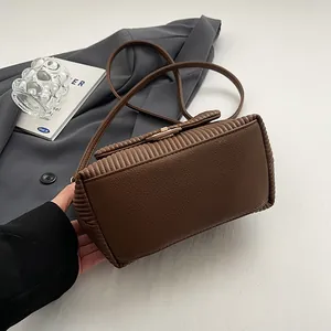 Dettaglio della pelle a pieghe marrone e della fibbia dorata su una borsa a tracolla