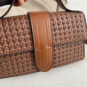 Close-up of the woven leather texture and brown stitching detail on the luxury handbag