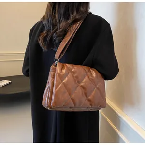 Détail du sac à bandoulière en similicuir matelassé marron avec large sangle et losanges