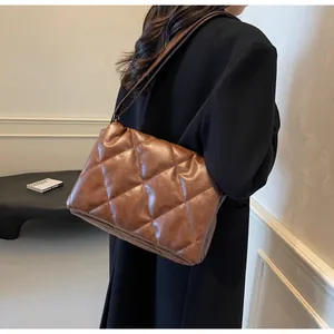 Détail d'un sac bandoulière matelassé marron avec texture douce porté par un mannequin