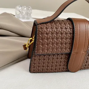 Detail shot of vintage brown woven leather handbag with caramel trim and gold buckle