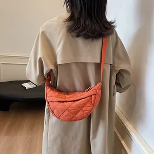 Rear view of a model wearing the orange quilted crescent crossbody bag with an adjustable strap