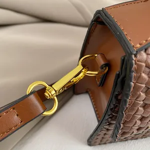Detail of woven brown leather side and gold metal lobster clasp on evening handbag